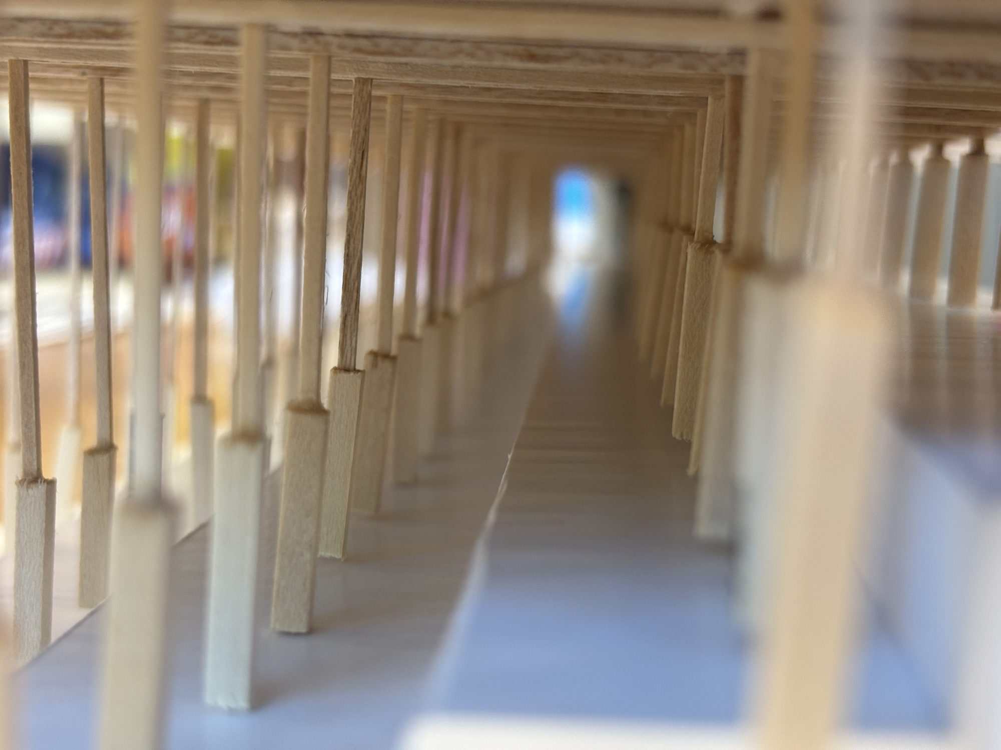 Eye-level view down a timber colonnade inside a model