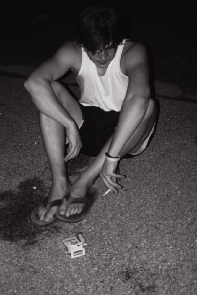 Figure crouched on the road at night, black and white