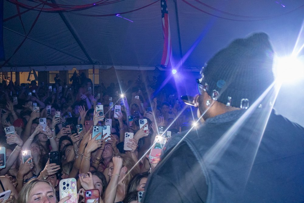 Performer silhouetted against a crowd of phone lights at a concert